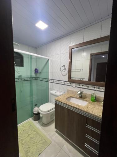 a bathroom with a toilet and a sink and a mirror at Recanto da Natureza in Matinhos