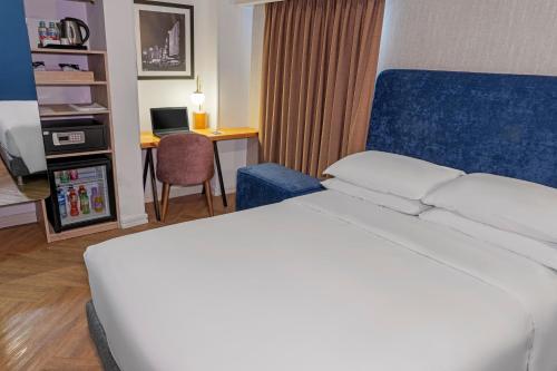 a hotel room with a white bed and a desk at Faranda Collection Cali, a member of Radisson Individuals in Cali
