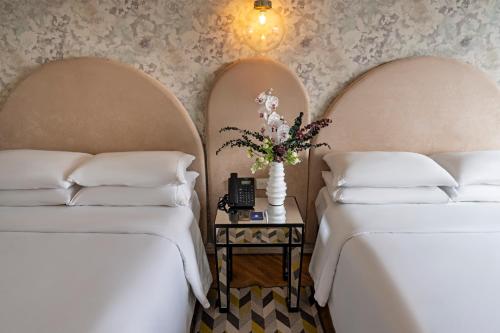 two beds with white sheets and a table with flowers at Faranda Collection Cali, a member of Radisson Individuals in Cali