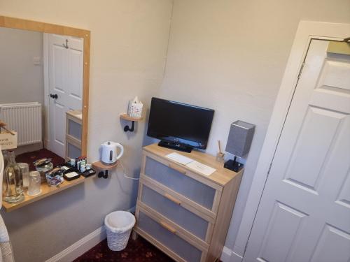 a bedroom with a television on a dresser with a desk at St Leonards Guest House in Largs