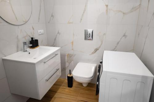 a white bathroom with a toilet and a sink at Przytulisko Leszczewek in Leszczewek