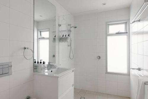 a white bathroom with a shower and a sink at Luxury On Lygon, Victorian Terrace in Melbourne