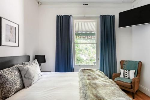 Un dormitorio con una cama y una ventana y una silla. en Re-Imagined Victorian Terrace Home, en Melbourne
