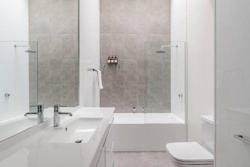 Un baño blanco con ducha y lavabo. en Re-Imagined Victorian Terrace Home, en Melbourne
