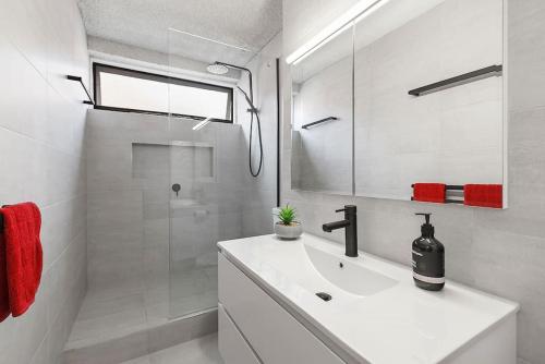a white bathroom with a sink and a shower at Bright, Stylist apartment in Richmond Terrace in Melbourne