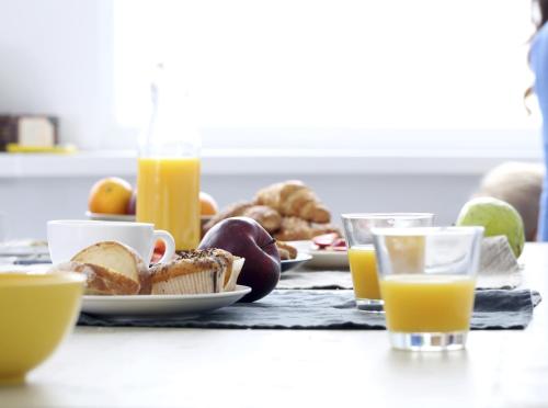 a table with plates of food and glasses of orange juice at Hotel Mermoz Paris Le Bourget in La Courneuve