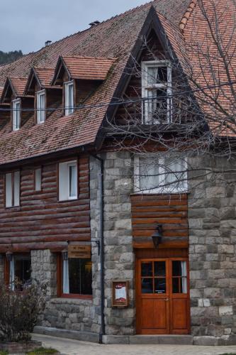 a stone house with a wooden door and windows at Hotel Turismo in San Martín de los Andes