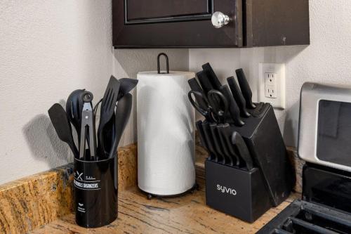 a counter with a knife block and a container of knives at Stylish Studio Apartment with Modern Touches in Peoria