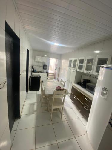 a white kitchen with a table and chairs in it at Casa in Garanhuns