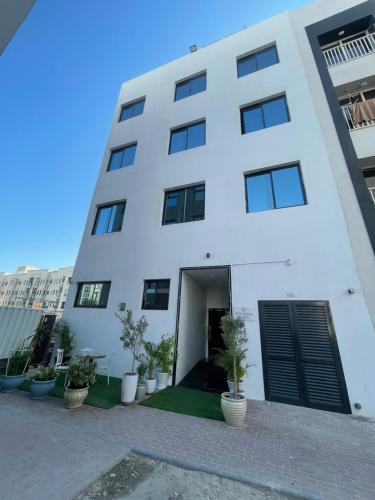 ein weißes Gebäude mit Pflanzen davor in der Unterkunft Ista Vacation Homes LLC in Dubai