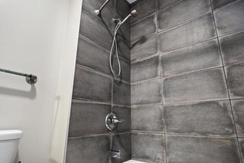 a bathroom with a shower with a tile wall at Chic Loft in Peoria Warehouse District in Peoria