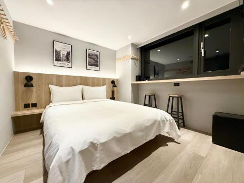 a bedroom with a white bed and a large window at N2 Hotel in Taichung