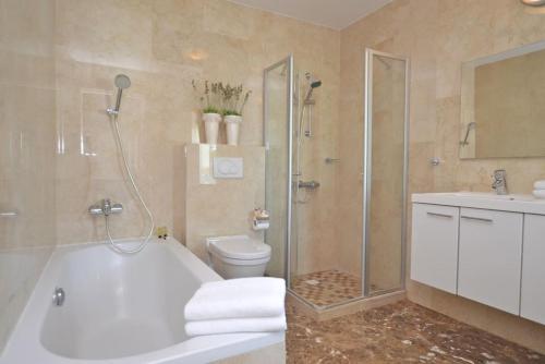 Un baño con bañera, inodoro y ducha. en Private 7BR Luxury Villa and Pool walk to Palm Beach, en Palm-Eagle Beach
