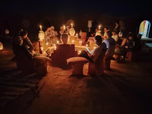 a group of people sitting in a dark room with candles at Luxury Desert Camp Erg Chegaga in El Gouera
