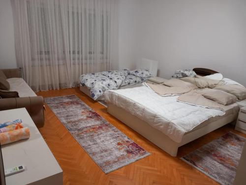 GjakoveにあるDomi Apartmentのベッドルーム1室(ベッド2台、ラグ2枚付)