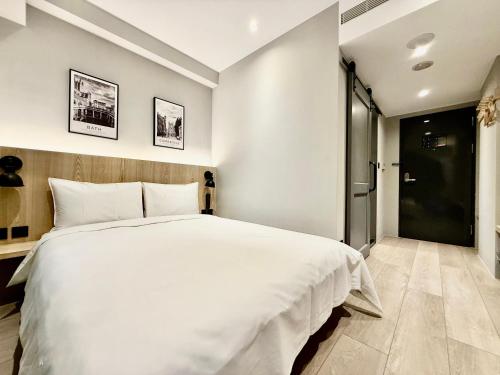 a bedroom with a large white bed and a door at N2 Hotel in Taichung