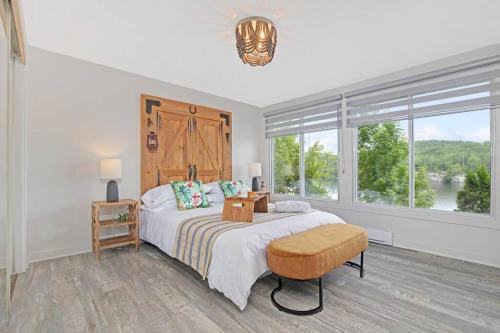 a white bedroom with a large bed and a window at Twin Lake Retreat - Hot Tub & Private Beach in L'Ange-Gardien