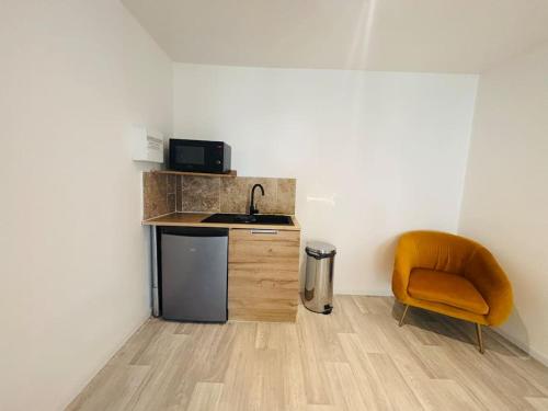 - une cuisine avec un évier et une chaise orange dans l'établissement Charmant Studio 1 avec Jacuzzi à Quéven, à Quéven
