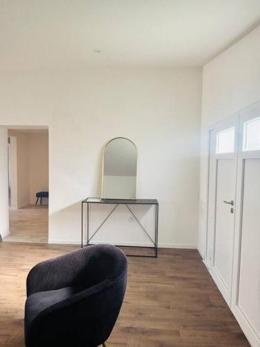 - un salon avec une chaise noire et un miroir dans l'établissement Charmant Studio 1 avec Jacuzzi à Quéven, à Quéven