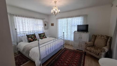 a bedroom with a bed and a chair and a television at Belle Vue Guesthouse in Hermanus