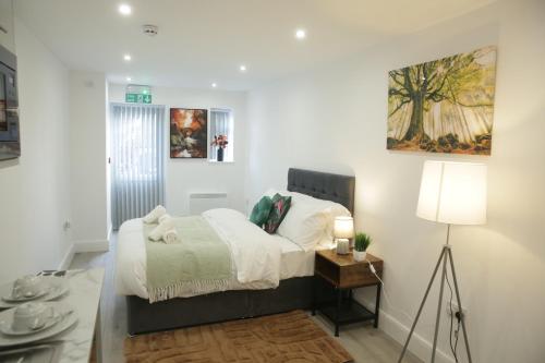 a white bedroom with a bed and a lamp at Luton Nook and Kitchen 4 mins to Luton AirPort in Luton