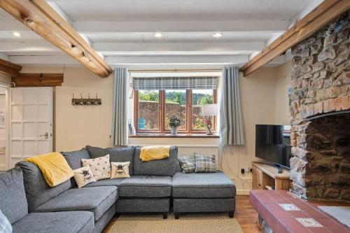 a living room with a gray couch and a stone fireplace at Beautiful Cottage Parking Central Dunster in Minehead