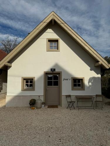 a white house with a door and two chairs at Prés-Lak in Tarján