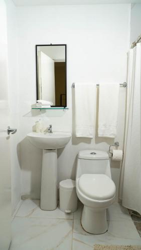 a white bathroom with a toilet and a sink at Hotel Ventura in Quesada
