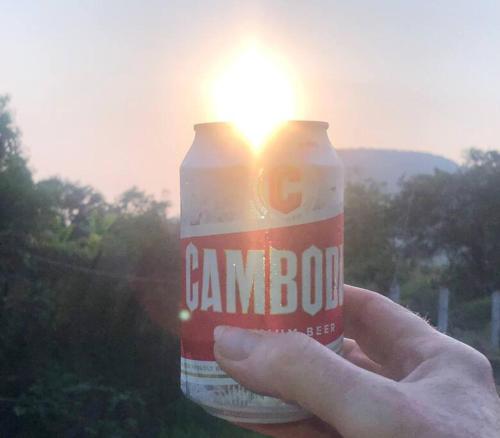 a person holding a can of beer with the sun in the background at Mountain View House Kampot in Kampot