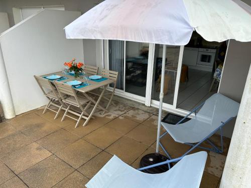 - une table, des chaises et un parasol sur la terrasse dans l'établissement appartement en front de mer, à Guidel