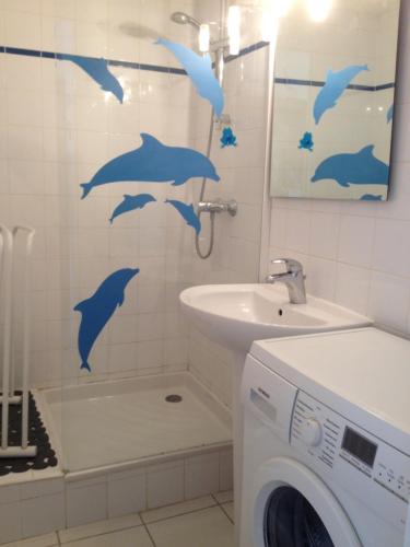 La salle de bains est pourvue d'une douche avec des dauphins sur le mur. dans l'établissement appartement en front de mer, à Guidel