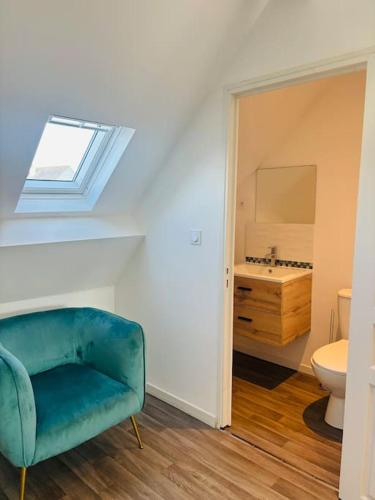 d'un salon avec une chaise bleue et d'une salle de bains. dans l'établissement Charmant Studio 6 avec Jacuzzi à Quéven, à Quéven