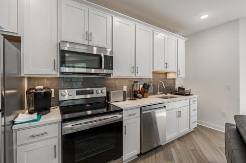 a kitchen with white cabinets and stainless steel appliances at Huguenot Apt - TH08 - Tourist Homes of Richmond in Richmond