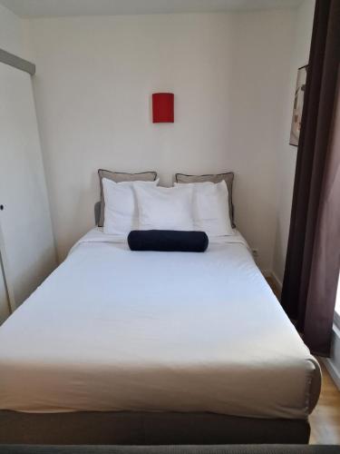 un lit avec des draps blancs et des oreillers dans une chambre dans l'établissement belle appartement au canal de saint martin, à Paris