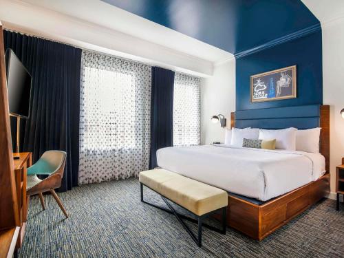 a hotel room with a large bed and a television at Hotel Belmont Vancouver - MGallery Collection in Vancouver