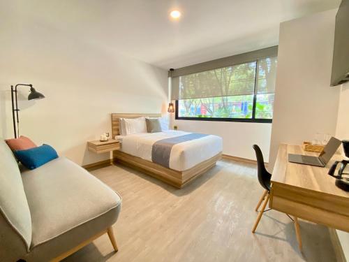 a bedroom with a bed and a chair and a window at Second Home Darwin in Mexico City