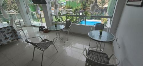 two tables and chairs in a room with a pool at Pacharodeo & Hospedaje in Pachacamac