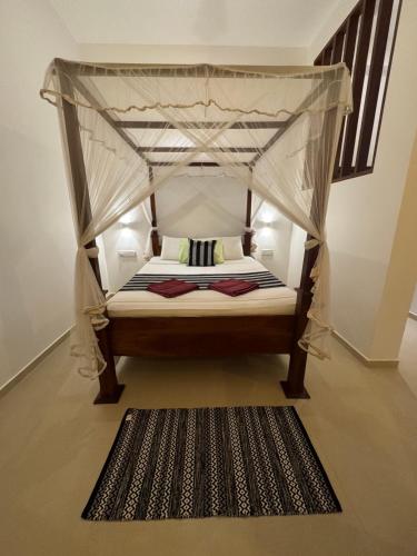 a bedroom with a canopy bed with a rug at Villa Red Lobster in Hikkaduwa