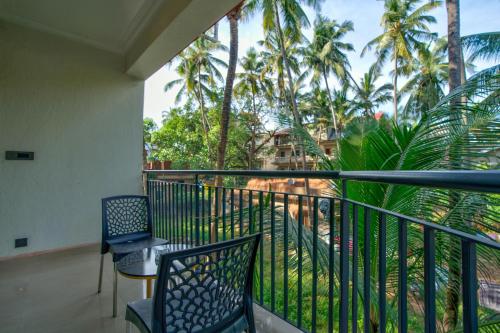a balcony with chairs and a table and palm trees at Dimaru Boutique Hotel in Calangute