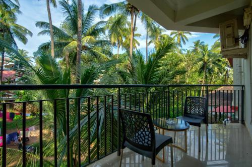 a balcony with two chairs and palm trees at Dimaru Boutique Hotel in Calangute