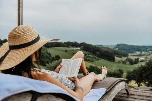 a woman sitting in a hammock reading a book at Weingarten-Resort Unterlamm Loipersdorf - ADULTS ONLY in Unterlamm