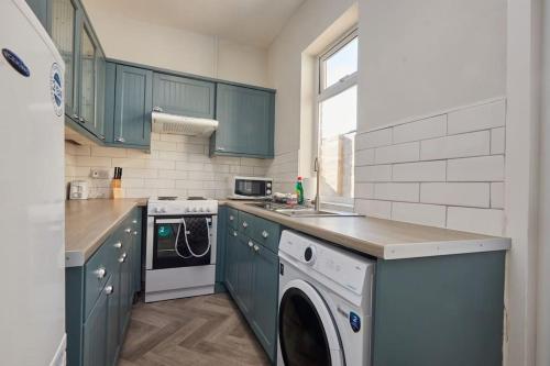 a kitchen with green cabinets and a washer and dryer at Cosy 3-Bedroom House With Street Parking in Stockton-on-Tees