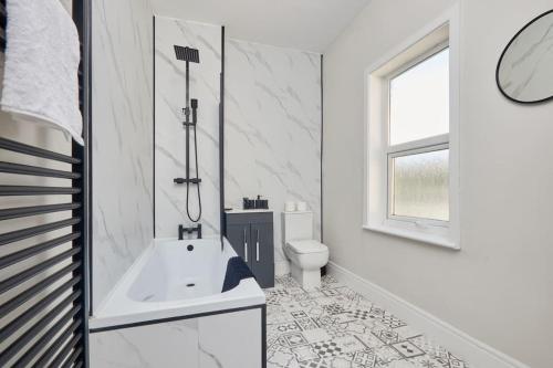 a white bathroom with a tub and a toilet at Cosy 3-Bedroom House With Street Parking in Stockton-on-Tees