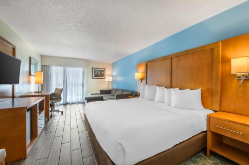 a hotel room with a large bed and a desk at Tropical Winds Resort Hotel in Daytona Beach