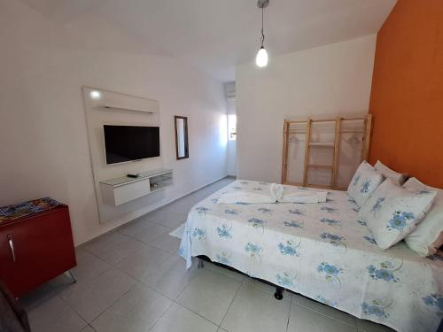 a bedroom with a bed and a flat screen tv at Pousada Água Viva in Ilha de Boipeba