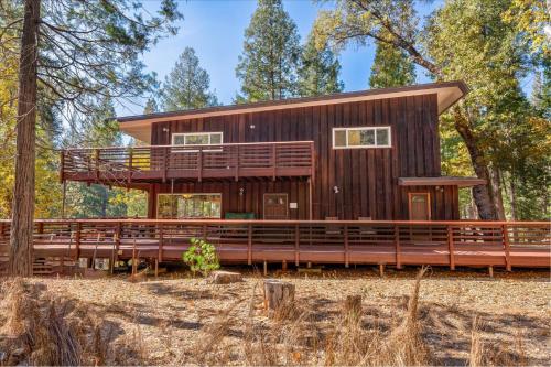 Una casa con una terraza envolvente en el bosque. en River's Edge w/ BBQ, Wifi, Firepit!, en North Wawona