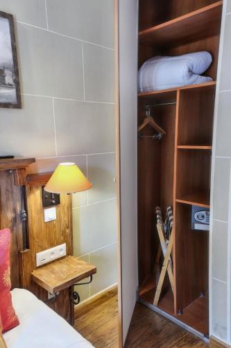 a room with a closet with a table and a lamp at Hôtel du Château in Vincennes