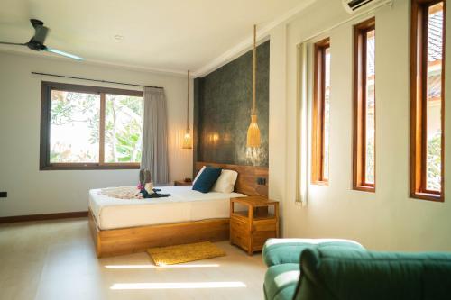 ein Schlafzimmer mit einem Bett und einer Couch in der Unterkunft Villa Trembesi in Kuta Lombok