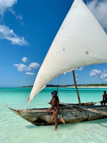 a woman standing on a boat on a beach at The View of Zanzibar in Michamvi
