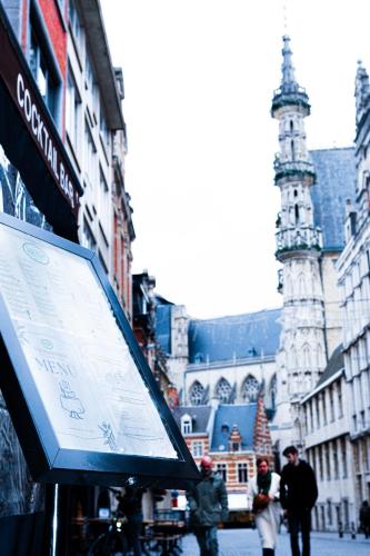 a sign in the middle of a city with a clock tower at Hotel Professor Leuven Centrum in Leuven